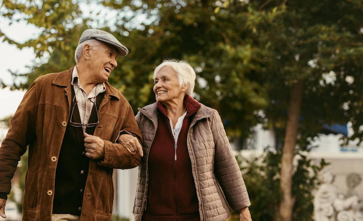 Elderly couple walking with their arms linked while laughing