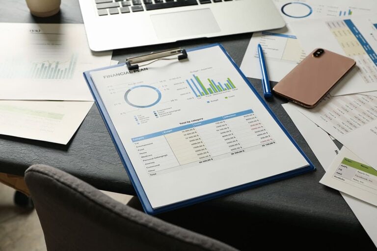A clipboard on a desk with papers labelled Financial Plan on it