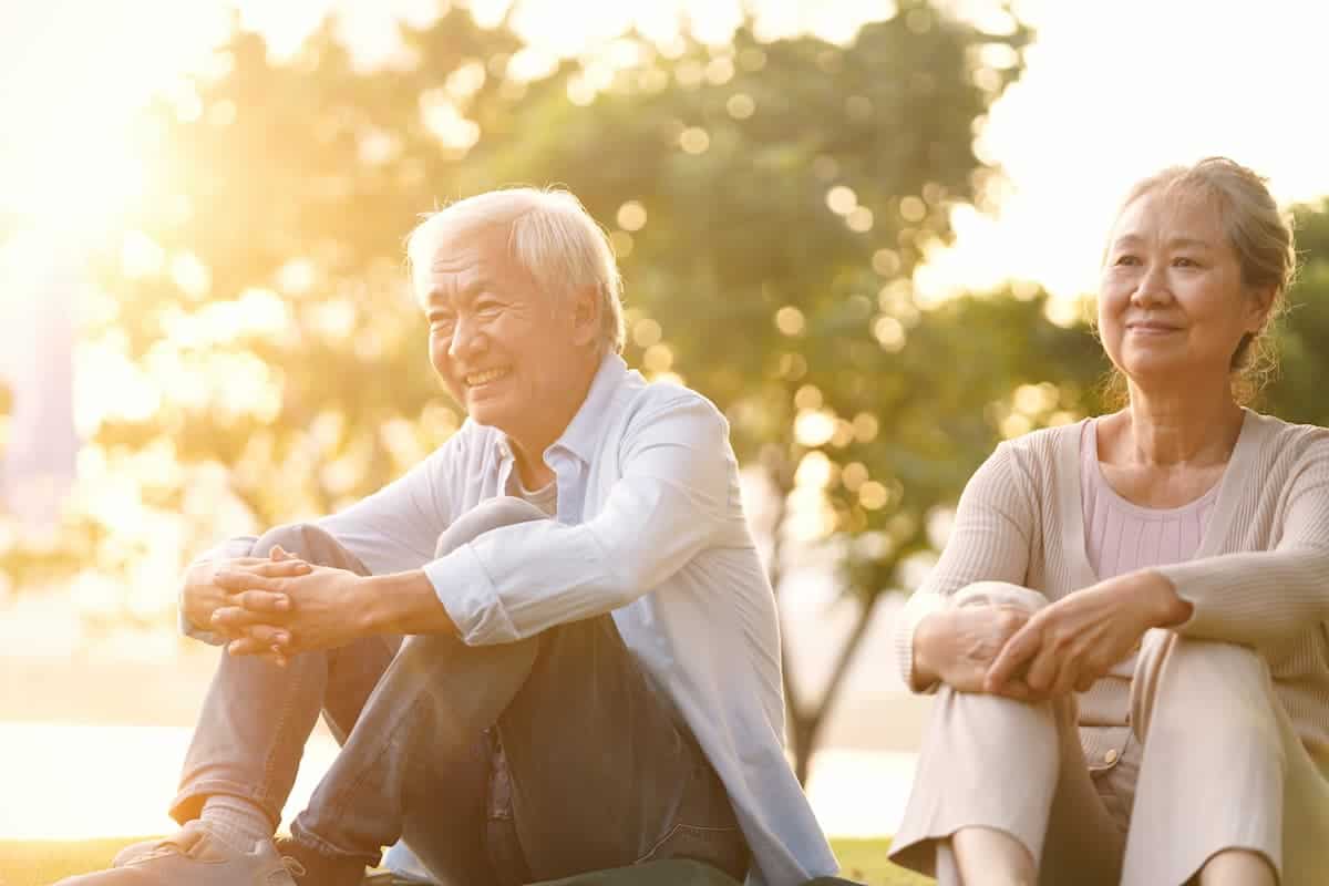 An elderly couple sitting in a park at sunset