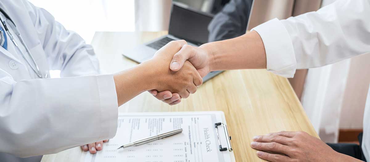 A closeup of a firm handshake taking place over an office desk