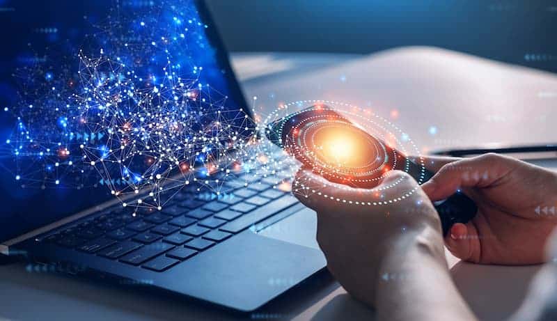 A pair of hands using a phone and laptop with light rings coming out of them