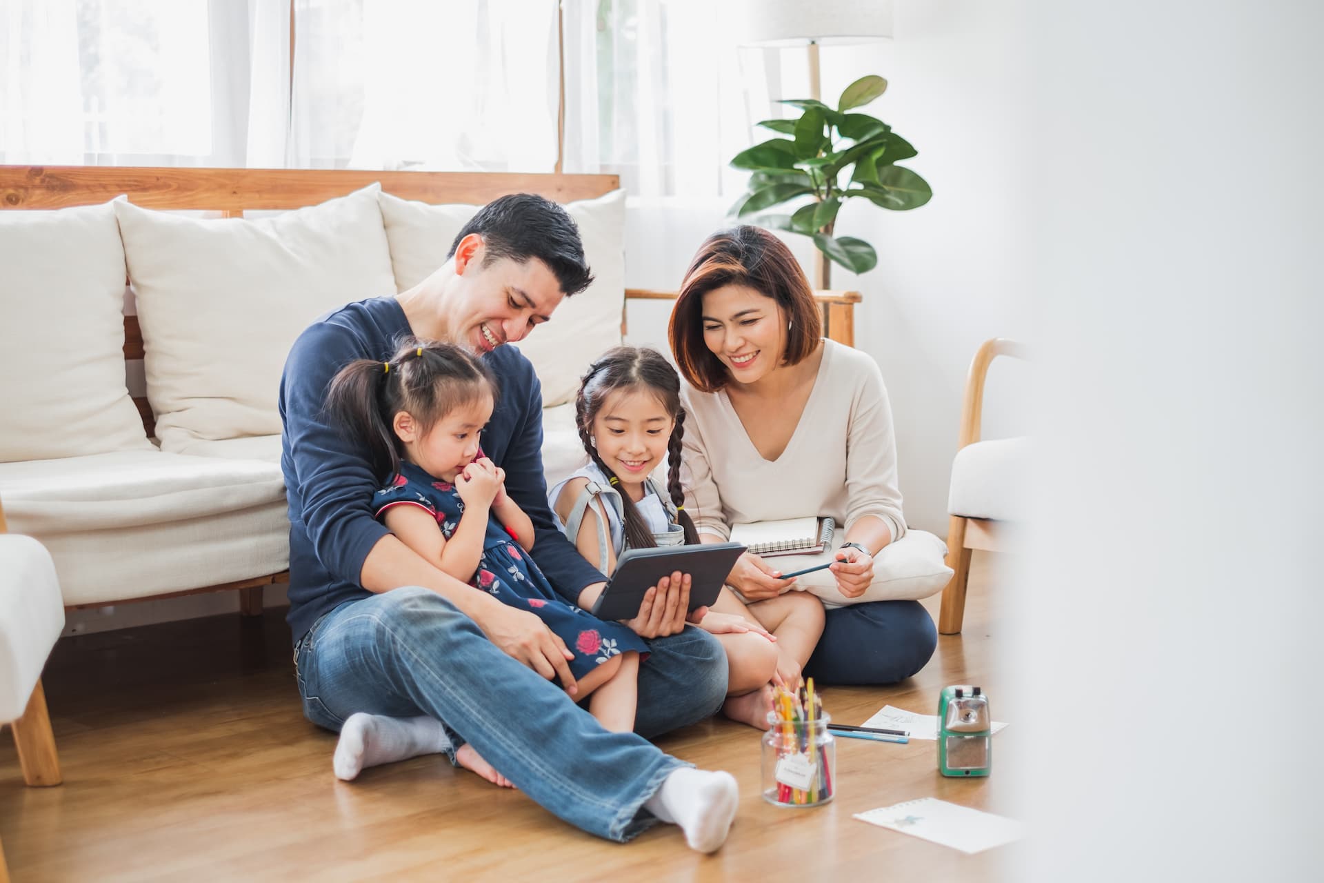 A happy family sitting on the floor looking at ipads