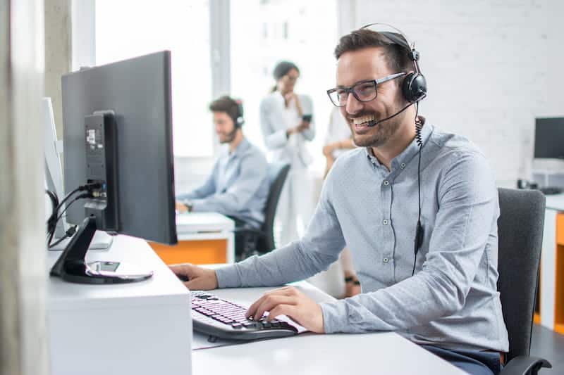 a person wearing a headset sitting at a desk with a computer