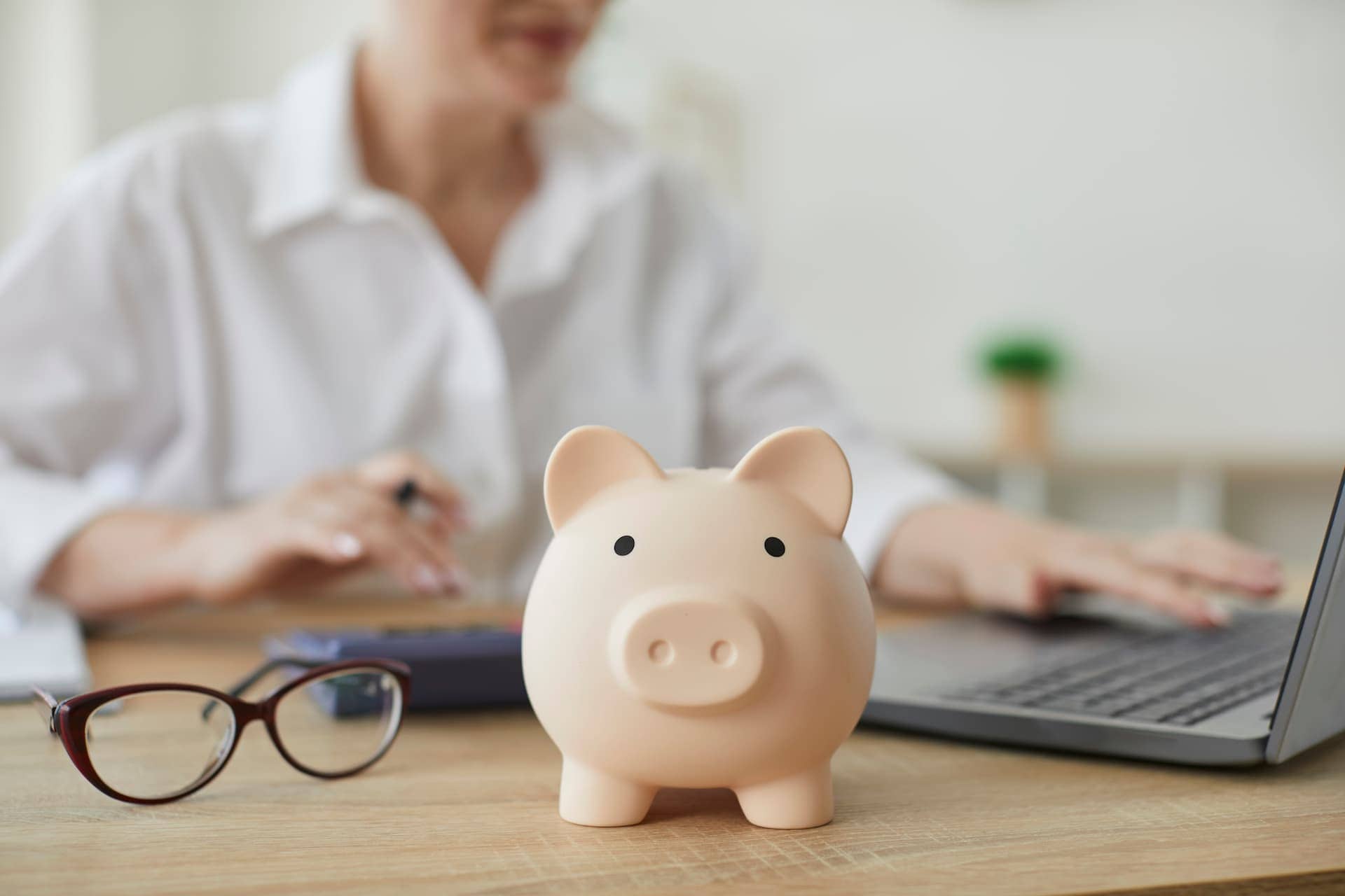 A piggy bank on a desk with a person sitting in the background