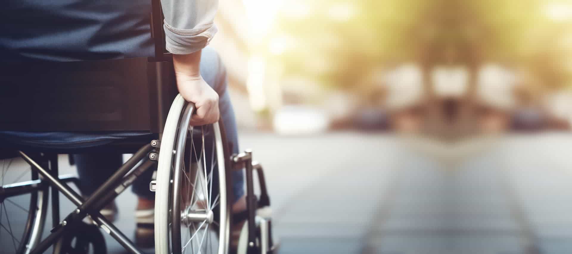 A person sitting in a wheelchair going down a sidewalk
