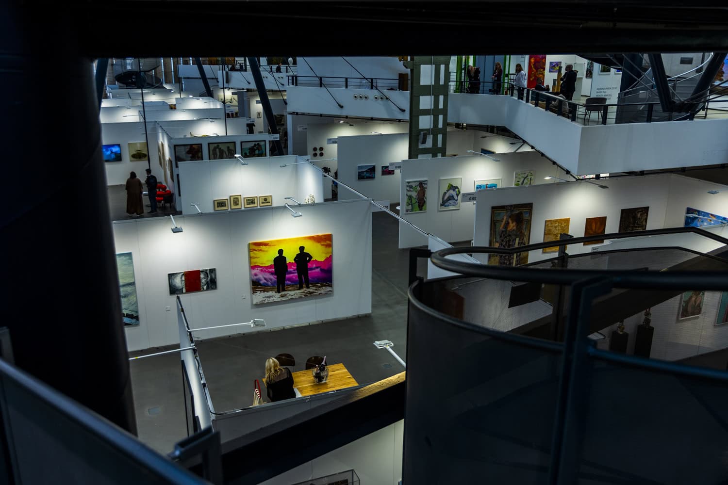 Modern art gallery interior with multi-level exhibition space displaying contemporary artwork and pa