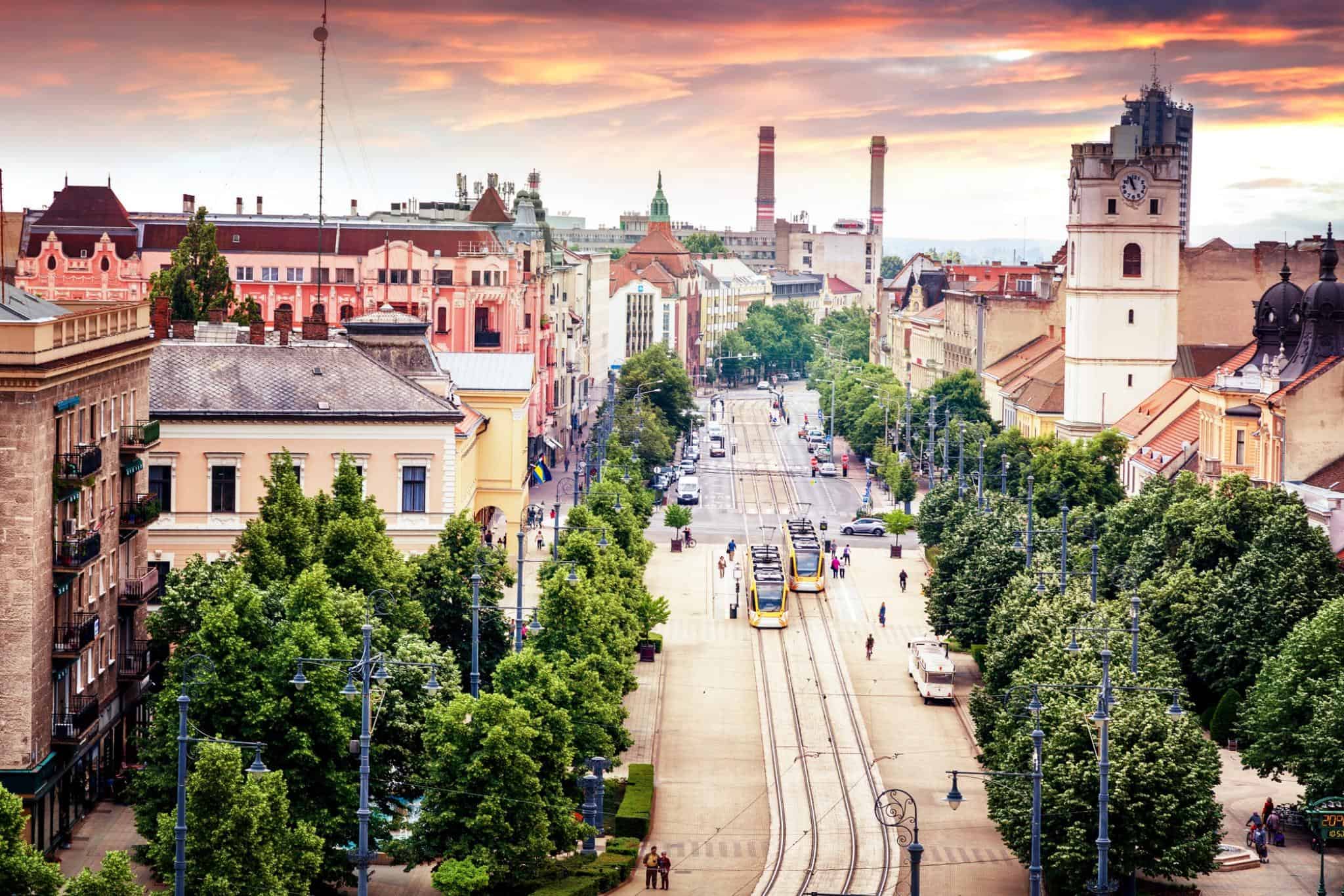 A panoramic view of Budapest city with historic buildings and tree-lined streets at sunset.