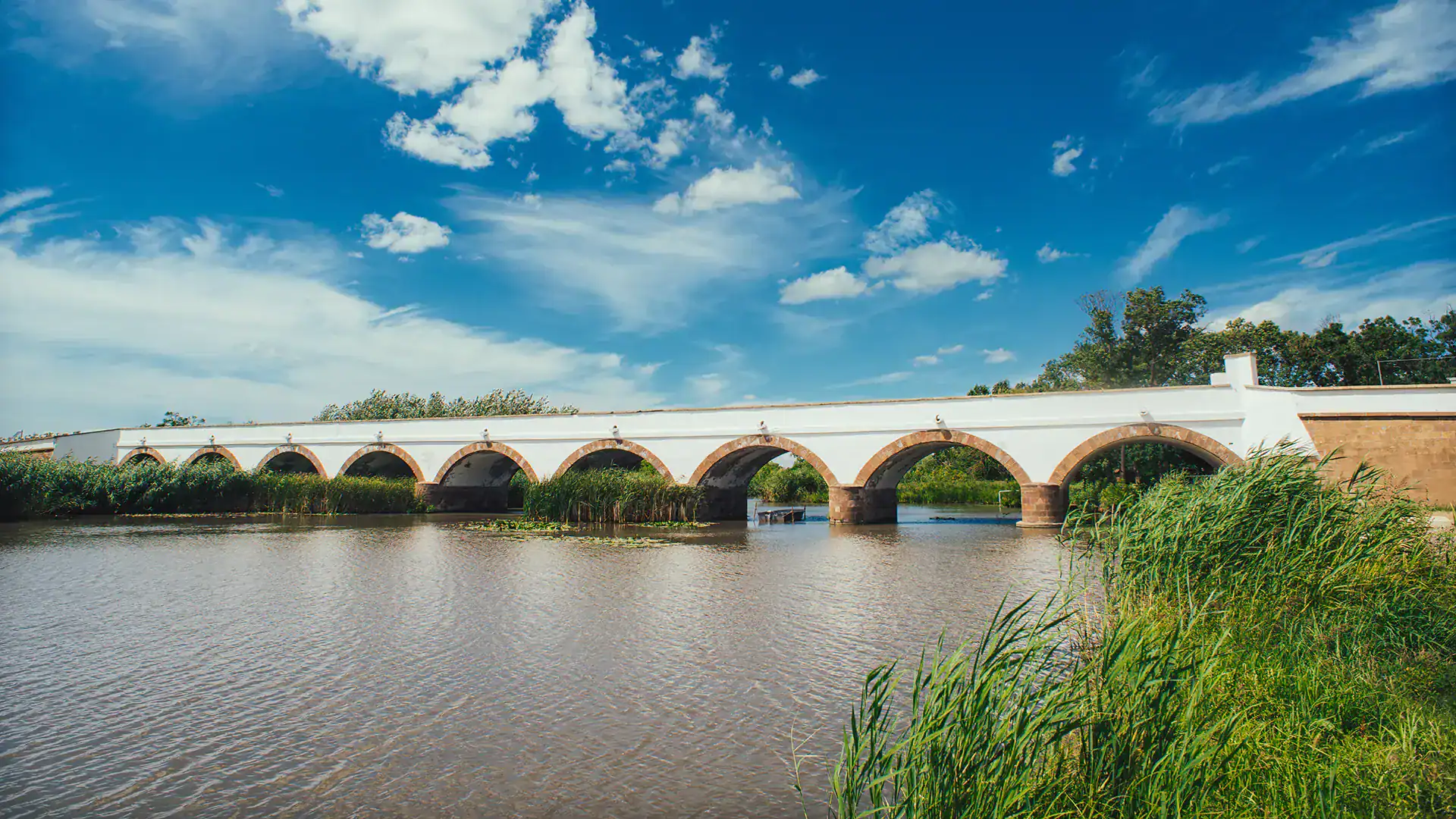 Historic arched bridge spanning the Danube River in Budapest under a blue sky.