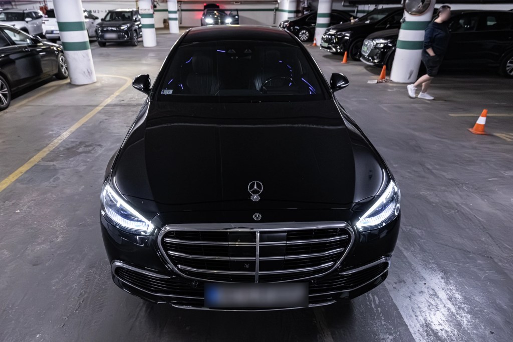 Black Mercedes-Benz S-Class sedan viewed from the front in an indoor garage.