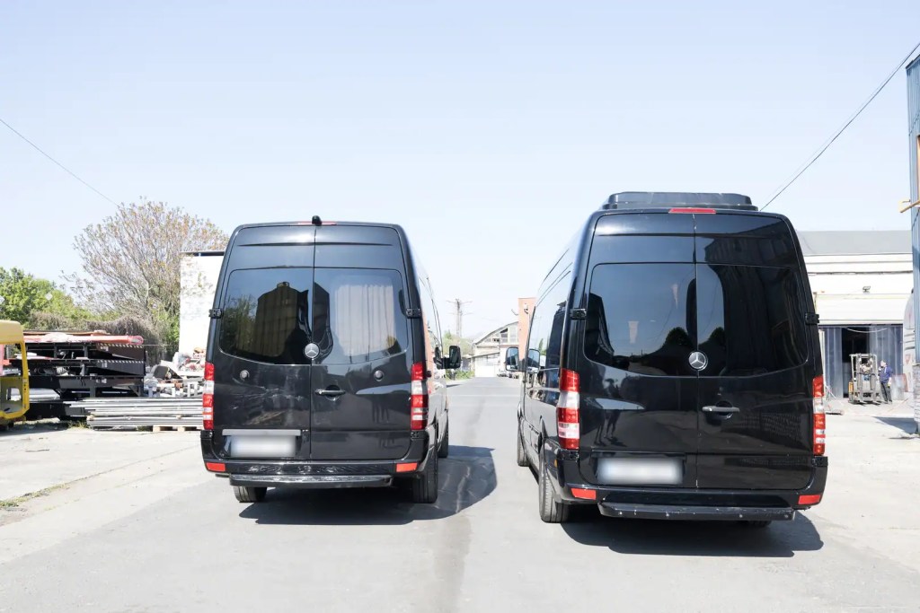 Rear exterior view of two black Mercedes-Benz Sprinter minibuses