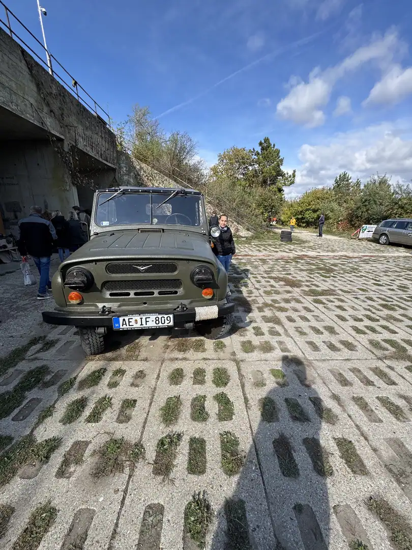 Olive military vehicle parked on the concrete grid surface in front of a bunker, under open sky