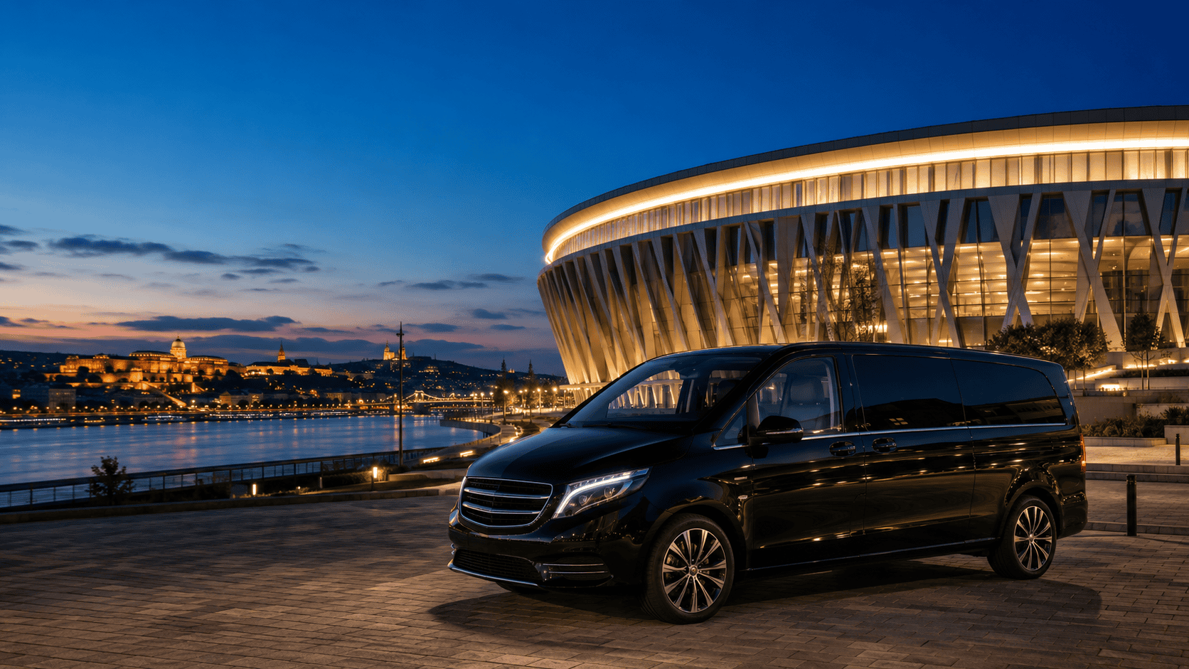 Black Mercedes van with chauffeur on the Danube embankment in Budapest at dusk — VanBudapest hourly chauffeur service