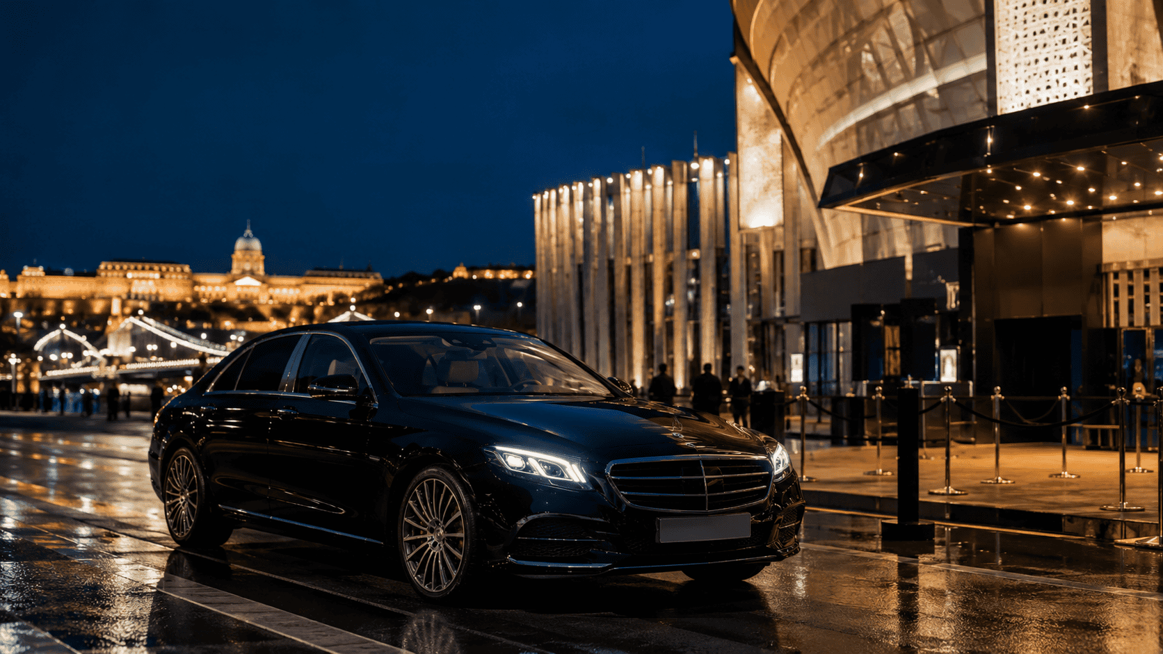 A black executive vehicle beside a Budapest event venue at night