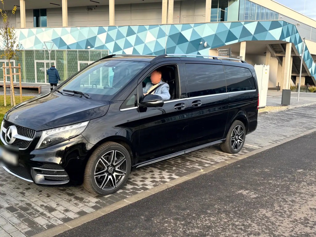 Schwarzer Mercedes-Benz V-Klasse und Chauffeur vor dem Terminal 2 des Flughafens Budapest