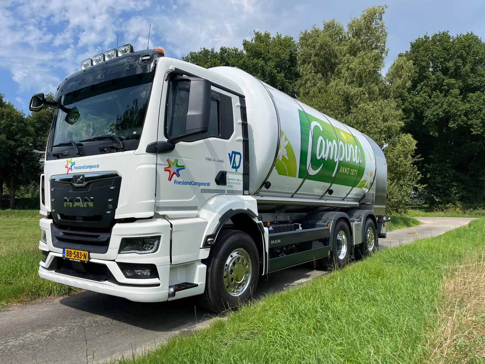 Zwarte en witte vrachtwagen met groene branding op weg naar campings in Friesland.