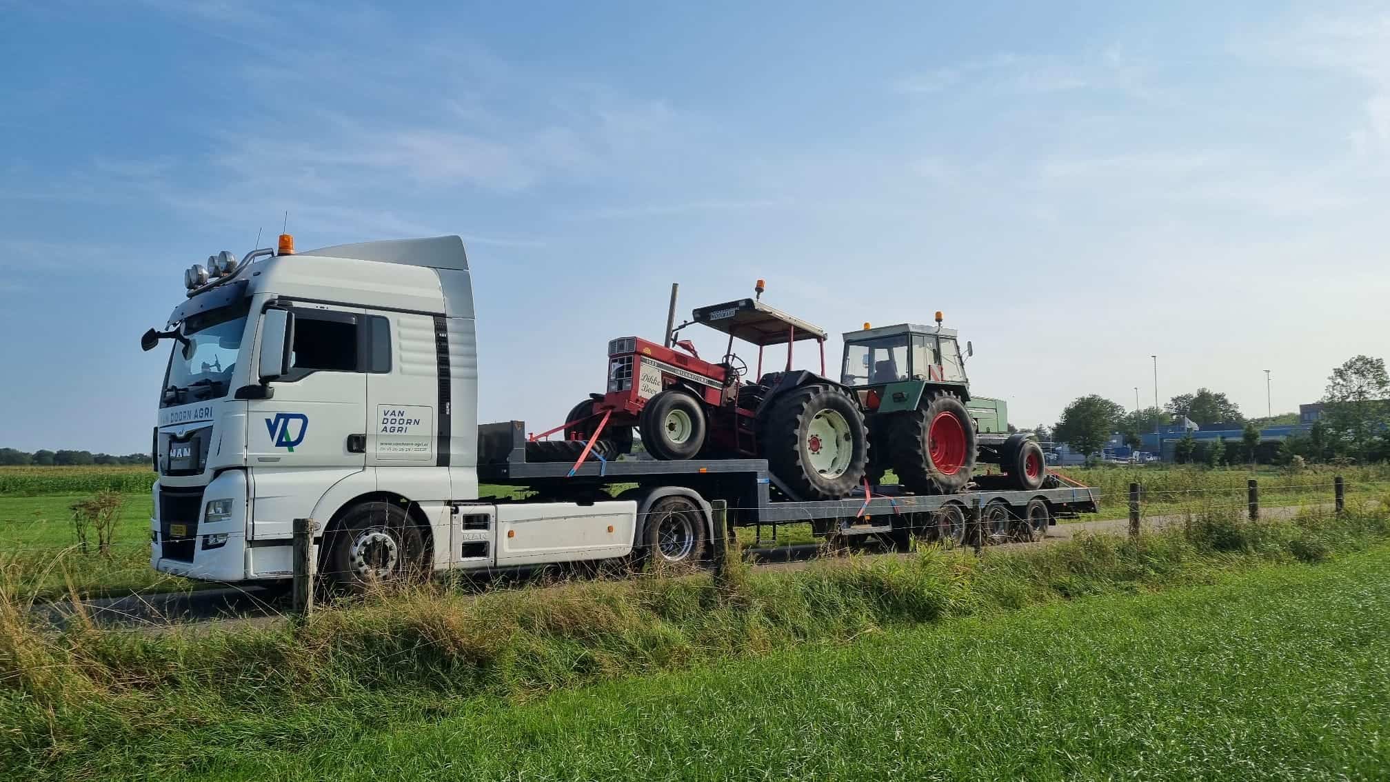 Veetransport met tractor en oude tractor op traject voor landbouwactiviteiten op het veld.