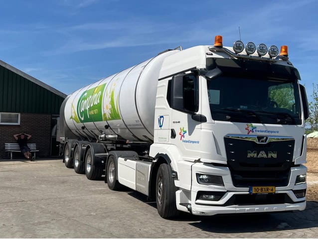 Grote witte transporttankwagen met logo op een parking.