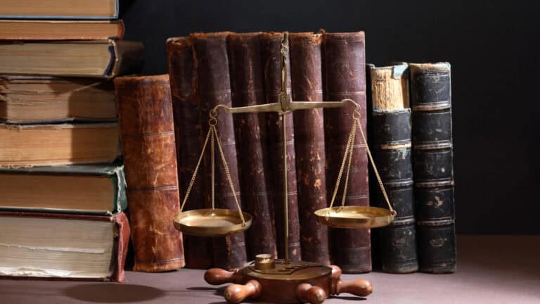 Scales of justice in front of old law books on a dark background.