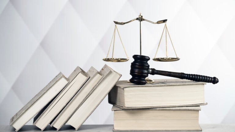 Legal books, gavel, and scales of justice on a desk.
