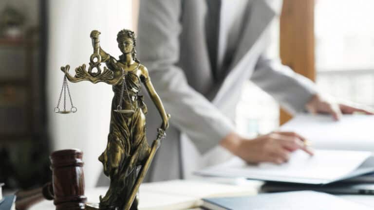 Statue of Lady Justice holding scales and sword in a legal office setting.