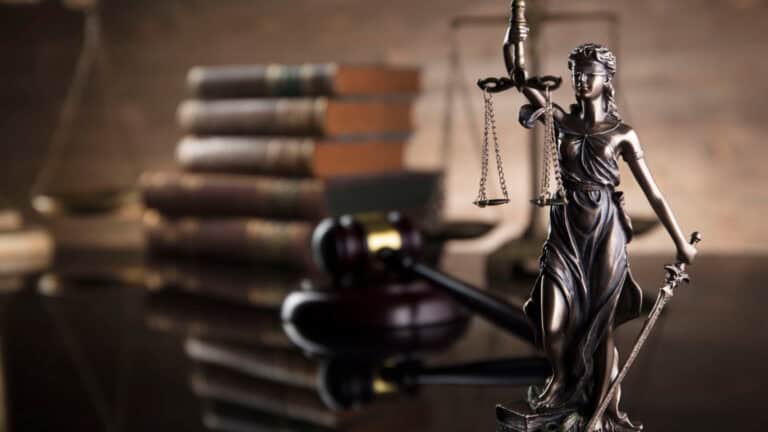Lady Justice statue with scales and sword in a legal office setting.