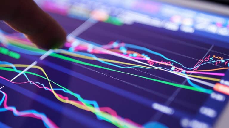 Close-up of a finger pointing at a digital stock market chart on a tablet.