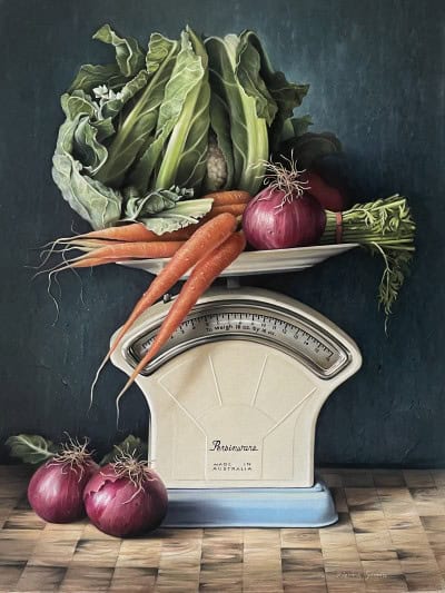 Fresh vegetables including carrots, lettuce, and onions displayed on a vintage kitchen scale.