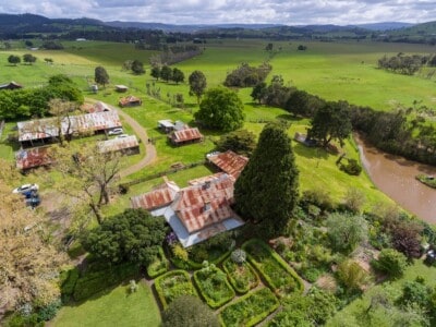 Aerial view of a Gulf Station with rustic buildings, lush greenery, and a river in Victoria, Australia.