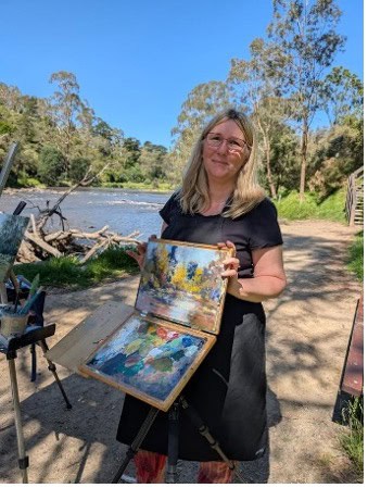 Woman painting outdoors at a pastel workshop by the river.