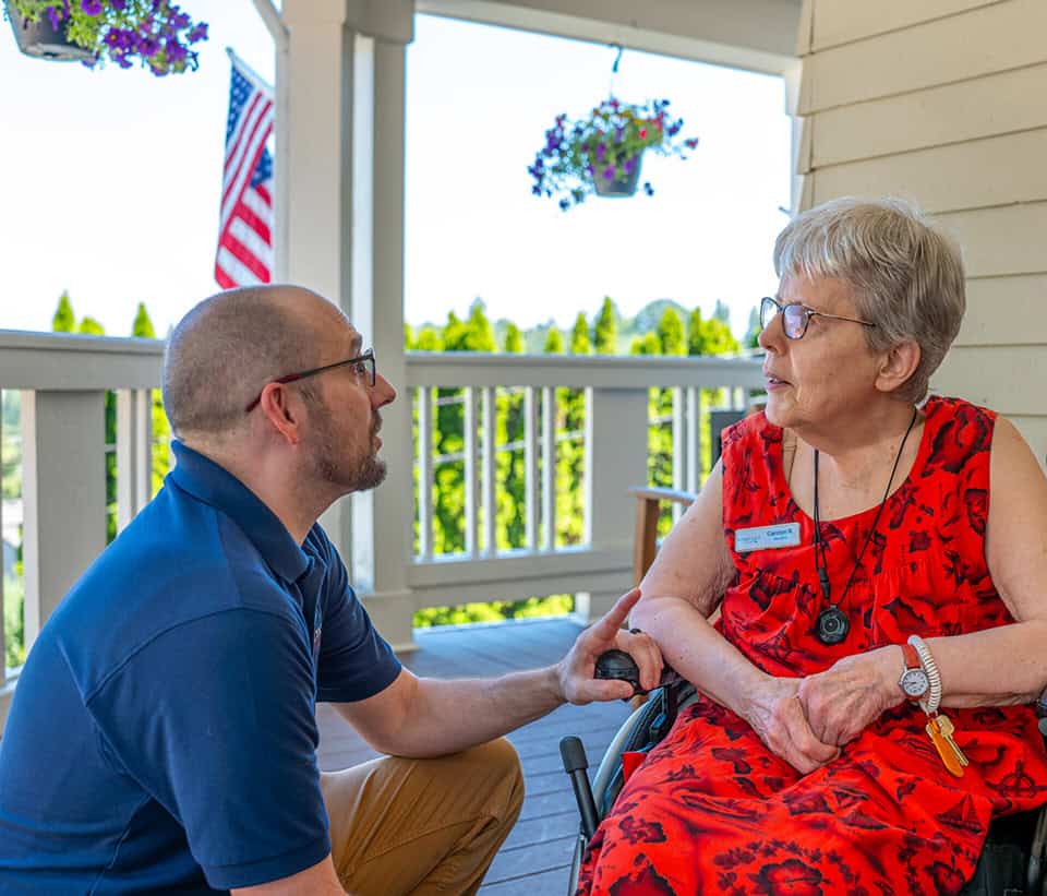 Assisted living resident with caregiver on porch.