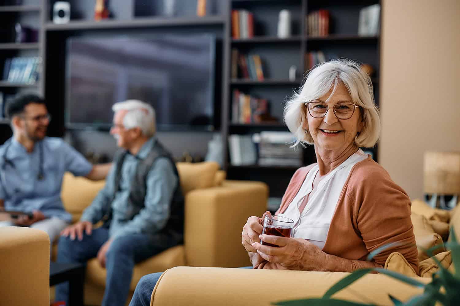 Senior woman enjoying a drink in an independent living community lounge.