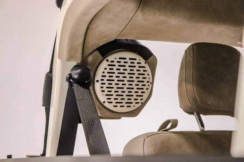 Round black and white speaker installed in the back of a vintage modern beige conference chair, showcasing retro-inspired industrial design elements.