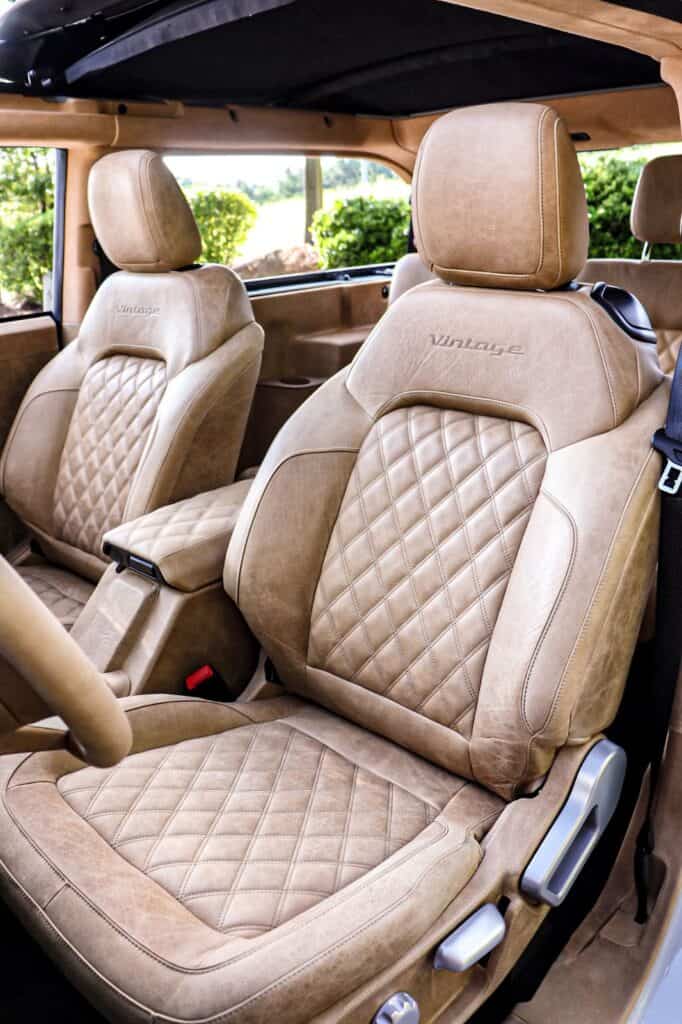 Luxurious beige leather vintage car seats with diamond quilting and embossed "Vintage" logo, showcasing classic interior design and premium craftsmanship.