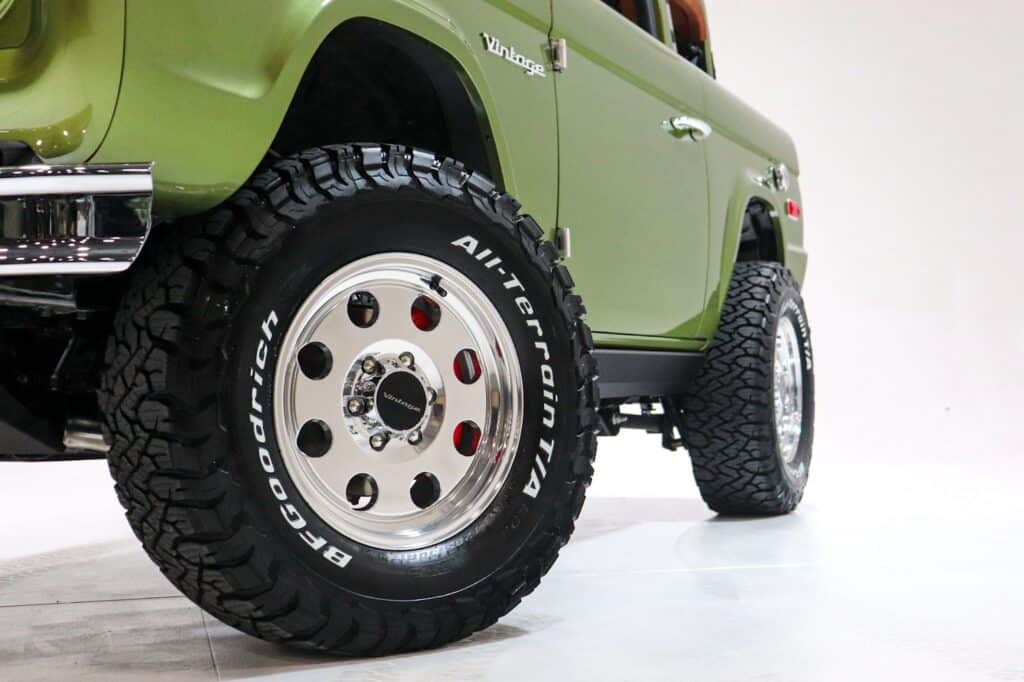 All-Terrain tires on vintage green off-road SUV with chrome accents, showcasing rugged durability and retro-modern style in automotive design.