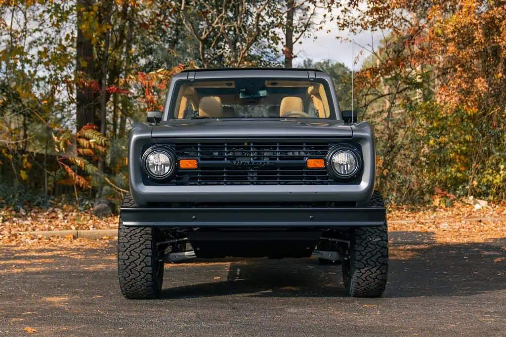 Vintage black off-road SUV with modern design, rugged tires, and autumn forest background, showcasing stylish outdoor vehicle for adventure and exploration.