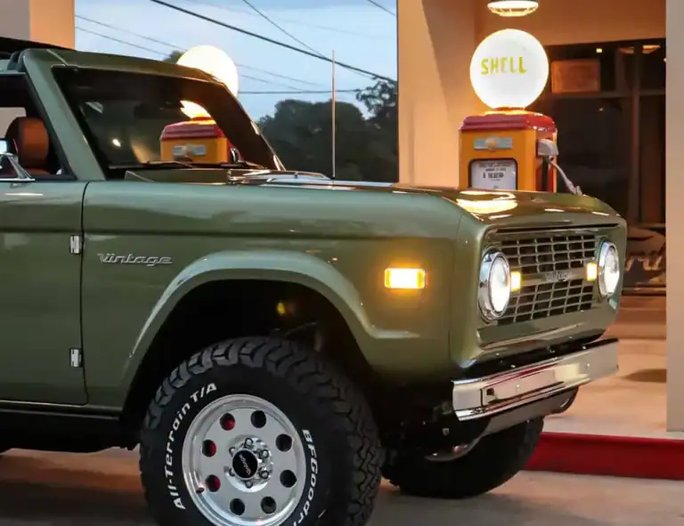 Vintage green classic truck parked by vintage Shell gas pump at retro service station, nostalgic automobile scene, American muscle car, vintage vibe, classic vehicle photography.