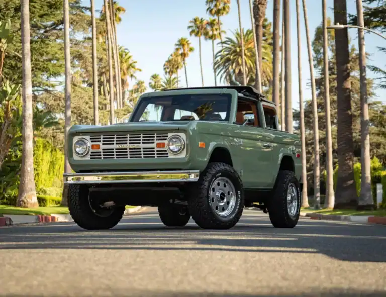 Classic vintage off-road vehicle in mint green parked on palm tree-lined street, showcasing retro style and rugged design.