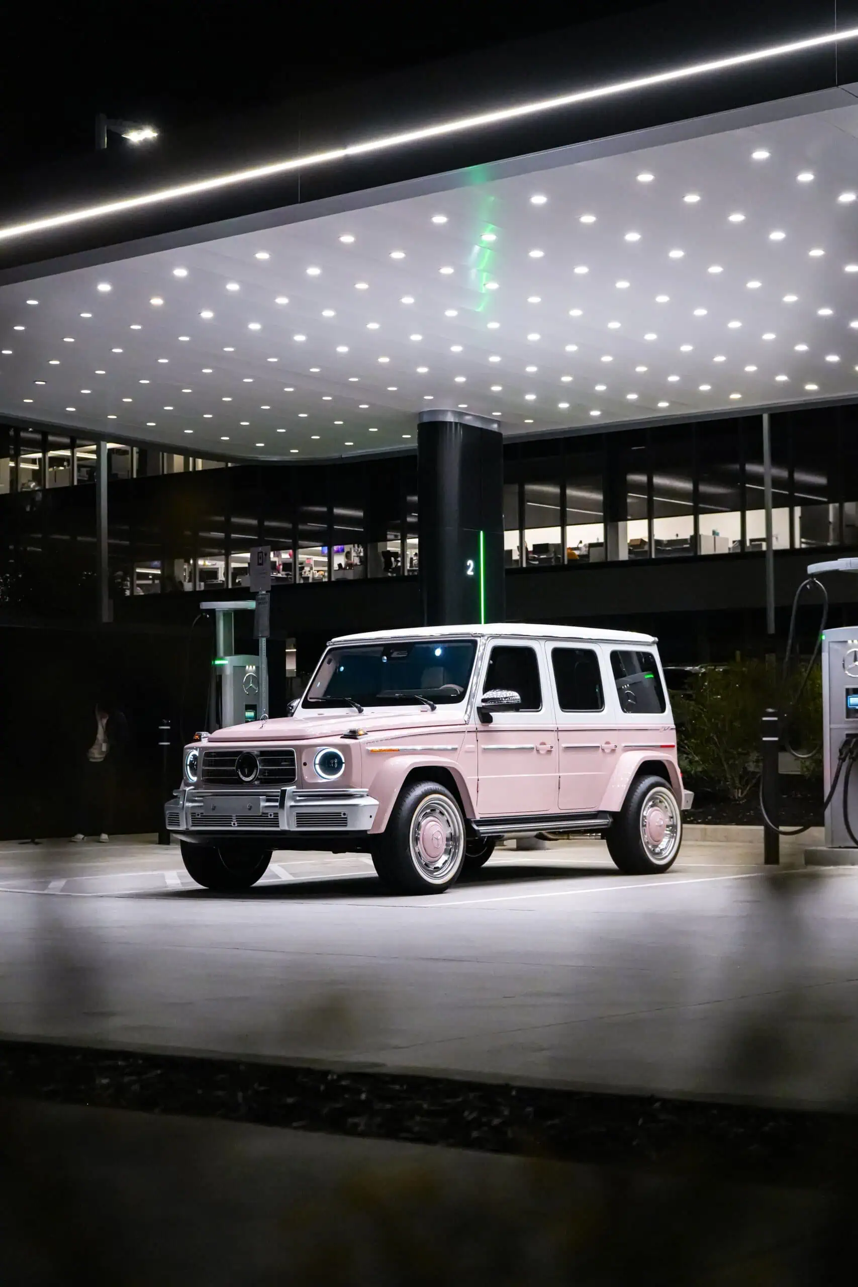 A stylish, vintage-inspired luxury SUV parked at a modern gas station under bright LED lights, showcasing a blend of classic design with contemporary urban aesthetics, perfect for a sophisticated lifestyle.