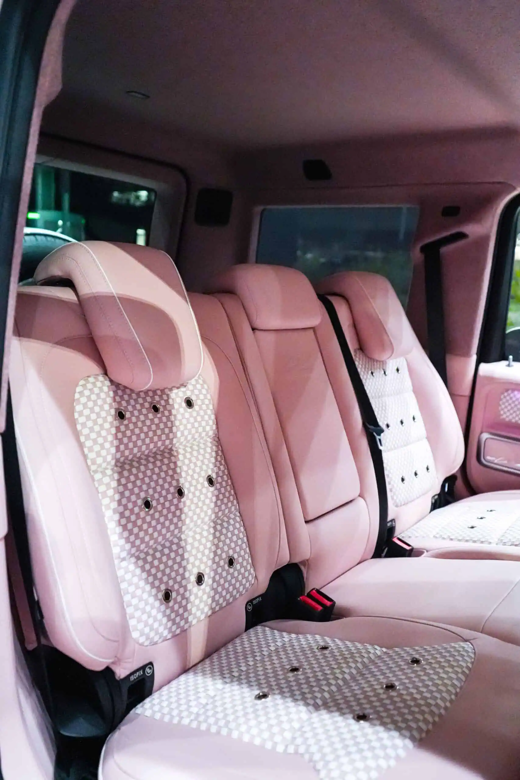 Stylish pink car seats with checkered pattern and headrest cushions, blending vintage charm and modern luxury for a sophisticated vehicle interior.