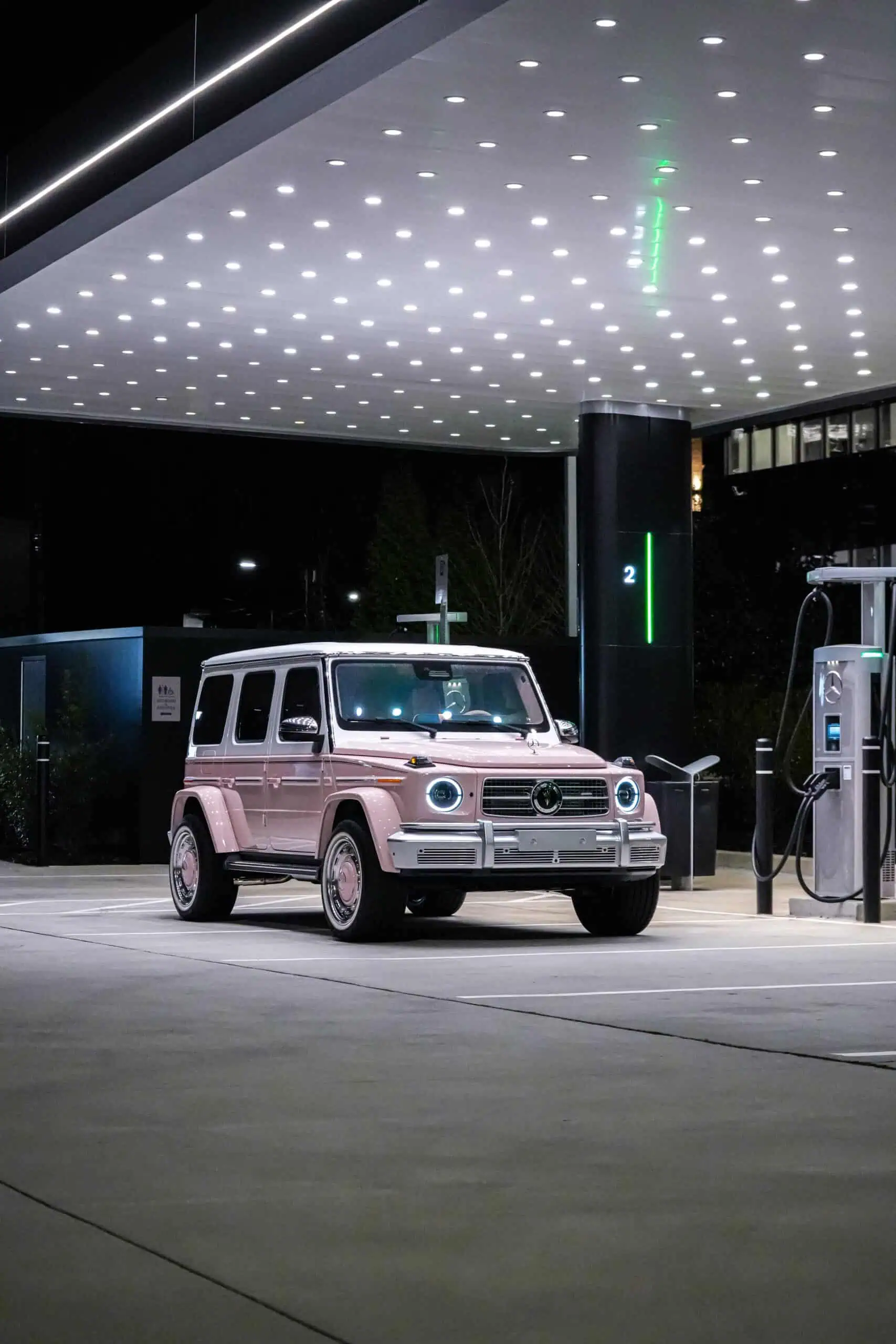 SUV parked at a modern gas station with sleek, illuminated ceiling design featuring LED lights, showcasing contemporary architectural style with vintage-inspired vehicle.