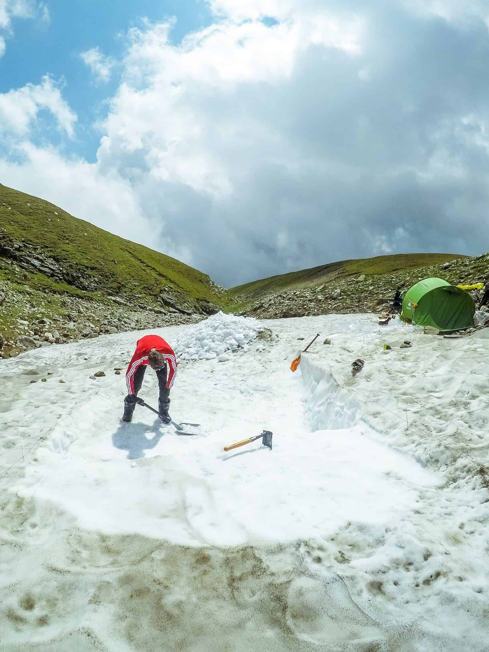 Hiker climbing snow-covered mountain during late winter, scenic landscape.
