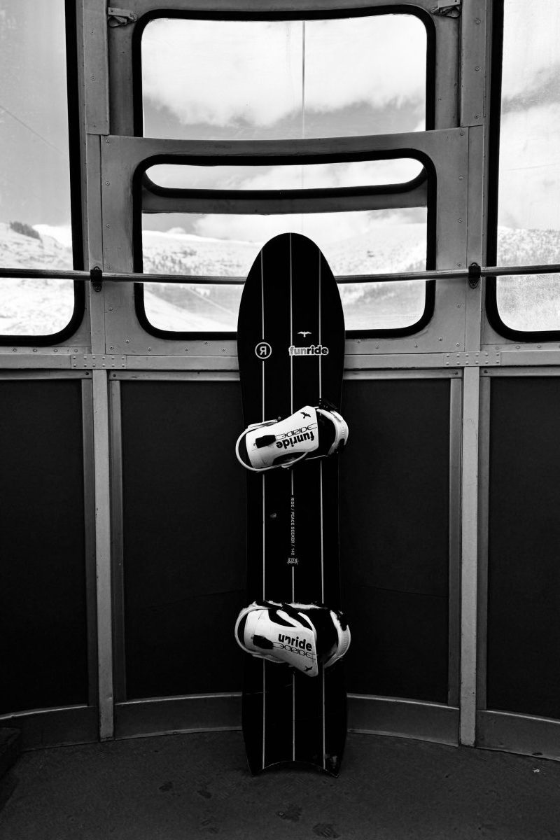 Echipament de snowboard și căști plasate în interiorul unei cabine, pregătite pentru aventură pe zăp.