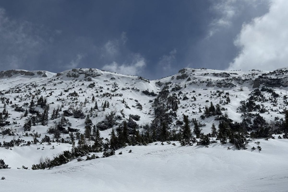 Peisaj montan înzăpezit cu cer noros, ideal pentru drumeții și aventuri în natură.