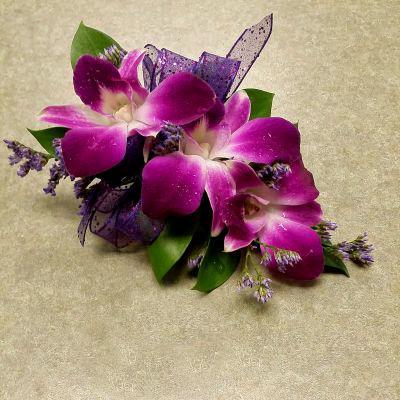 Beautiful wristlet corsage with how pink dendrobium orchids and purple filler.