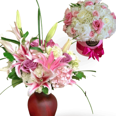 Elegant floral bouquet featuring pink and white lilies, roses, and hydrangeas in a red vase.