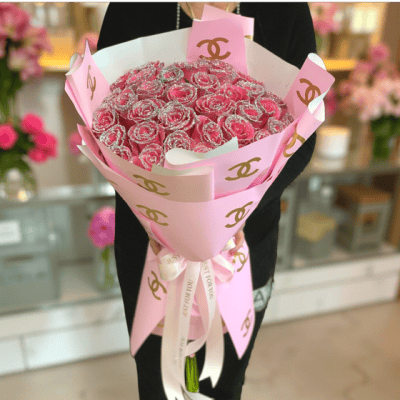 Pink Chanel-themed flower bouquet featuring a stunning arrangement of pink glitter roses, wrapped in elegant pink paper with gold Chanel logo accents, perfect for luxurious celebrations and special occasions.