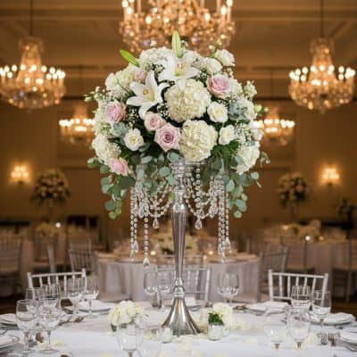 30 inch tall silver floral stand with hanging crystals featuring white hydrangeas blush pink roses white lilies and eucalyptus wedding centerpiece