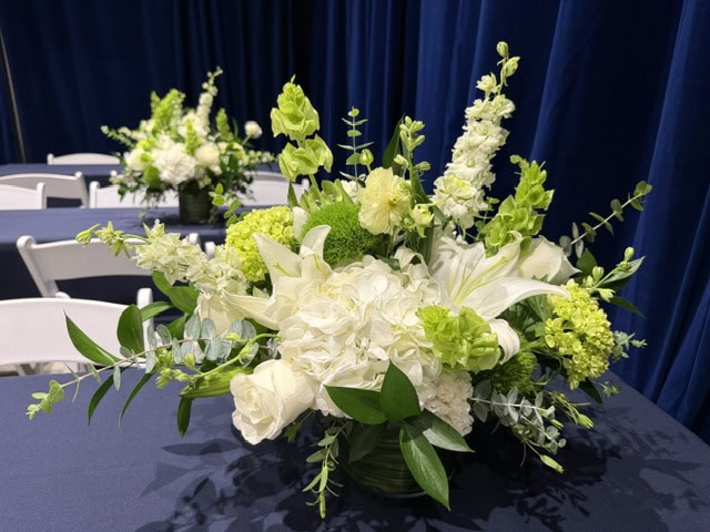 White and green floral centerpiece by a florist in Las Vegas featuring hydrangeas, roses, lilies, larkspur, green dianthus, viburnum, and eucalyptus.