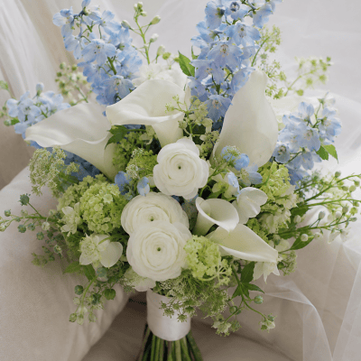 Royal Azure luxury bridal bouquet with light blue delphinium, white calla lilies, white ranunculus and pale green hydrangea