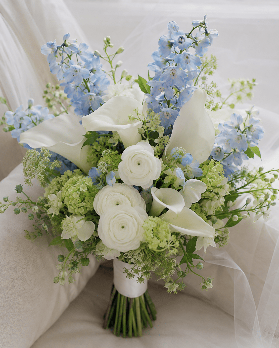 Royal Azure luxury bridal bouquet with light blue delphinium, white calla lilies, white ranunculus and pale green hydrangea